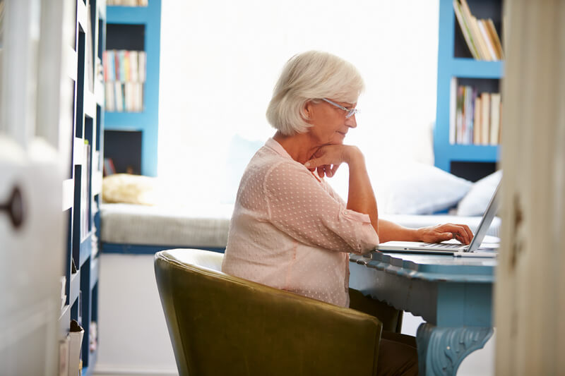 Senior Woman At Desk Working In Home Office With Laptop