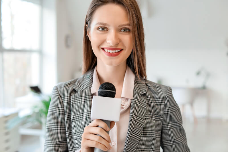 Female journalist with microphone in office