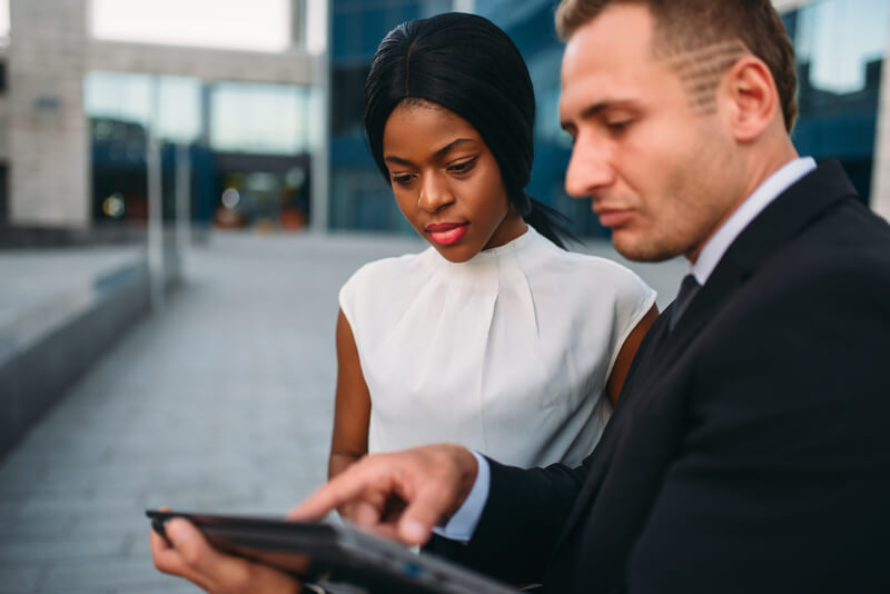 Business woman and businessman looks on laptop