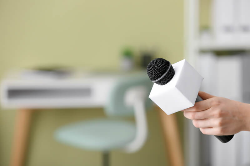 Female journalist with microphone having an interview indoors