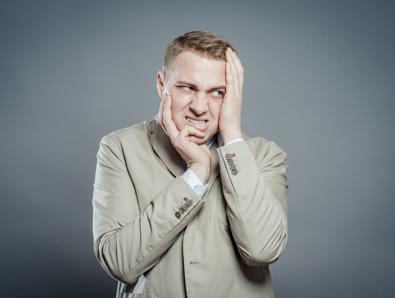 Expressions. Handsome young man in suit feeling fear with open mouth and closing eyes with hands