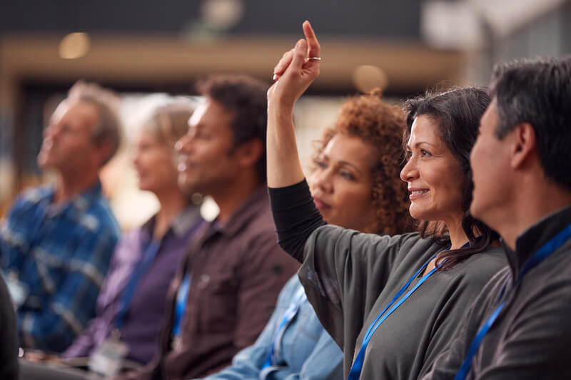 Businesswoman In Presentation At Conference Raising Hand To Ask Question