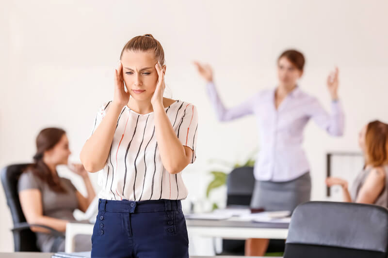 Stressed woman with headache and noisy people in office